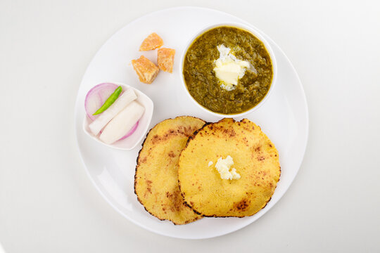 Top view of sarson ka saag with makki ki roti in plate on white background
