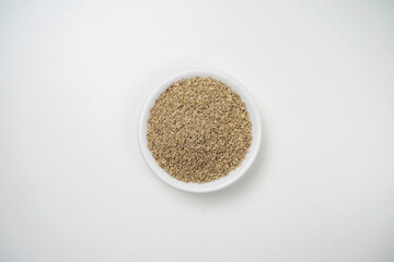 Top view of carom seeds in bowl on white background, ajwian