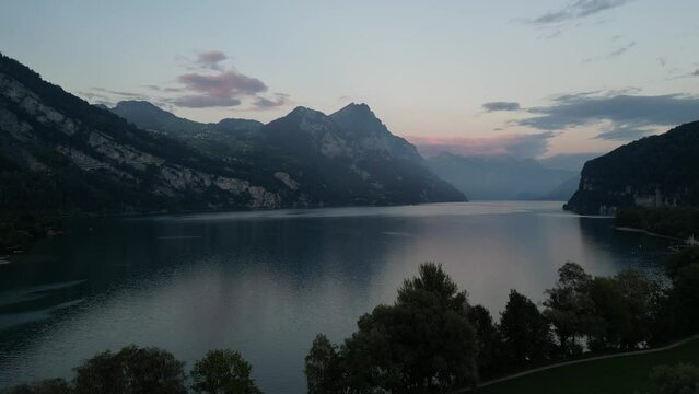 A magnificent view of Walensee Lake amidst mountain scenery and a pink-blue morning sky