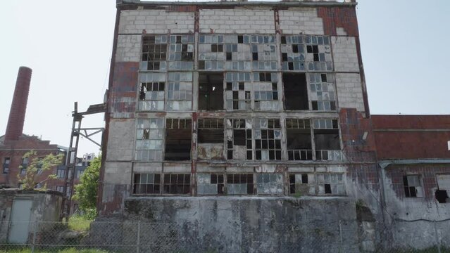 large, abandoned building with broken windows. The building is in a rural area of Cukrownia Żnin in Poland. Tilt-up shot.