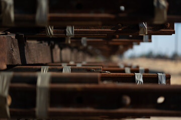 Closeup of a neat stack of materials for laying train tracks: railway sleepers (railroad ties) and steel rails are tidily arranged.