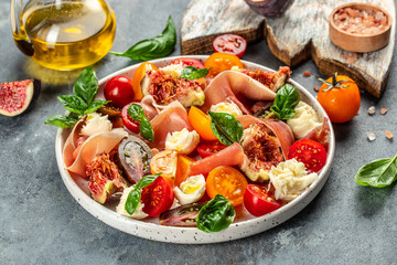 delicious figs, mozzarella, figs, prosciutto, fresh basil leaves and tomato salad, Concept healthy and balanced eating. place for text, top view