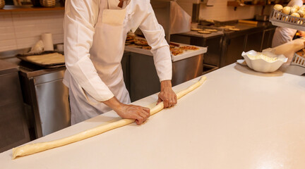 The cook rolls out the dough in the kitchen