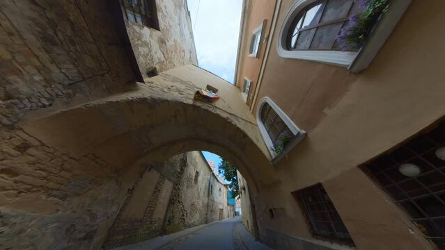 Lithuanian Flag Above the Arch in the Narrow Old Town Street in Vilnius, Lithuania.  Wide Angle Slomo Footage.