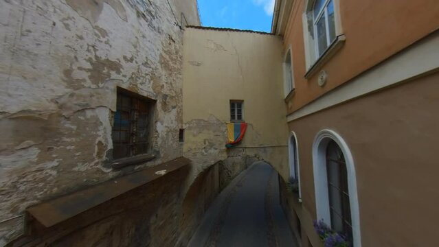 Lithuanian Flag Above the Arch in the Narrow Old Town Street in Vilnius, Lithuania.  Wide Angle Slow Motion Footage