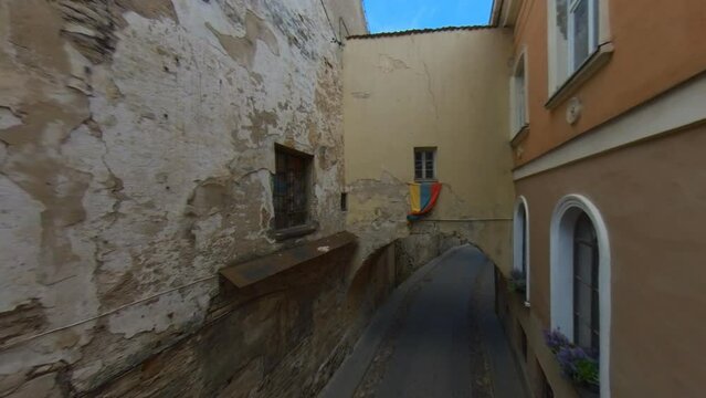 Lithuanian Flag Above the Arch in the Narrow Old Town Street in Vilnius, Lithuania.  Wide Angle Slow Motion Footage.