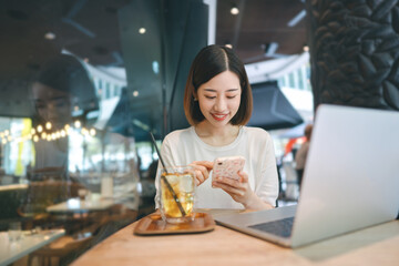 Business freelance asian woman using smartphone and laptop computer rest at cafe restaurant lifestyle