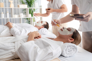 Fototapeta na wymiar Serene ambiance of spa salon, couple indulges in rejuvenating with luxurious face cream massage with modern daylight. Facial skin treatment and beauty care concept. Quiescent