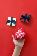 Hand holding gift boxes on red background.