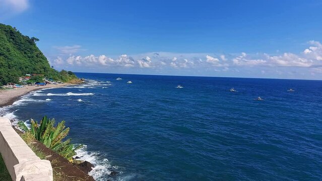 Cliff view of the ambient motion gentle waves and bobbing traditional basnigan fishing boats or outrigger boat in the coastal town of Basay Negros Oriental Philippines
