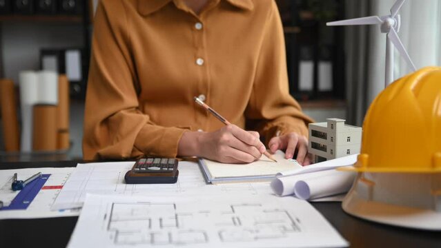 Creative architect projecting on the big drawings with architectural project at construction site at desk in office.