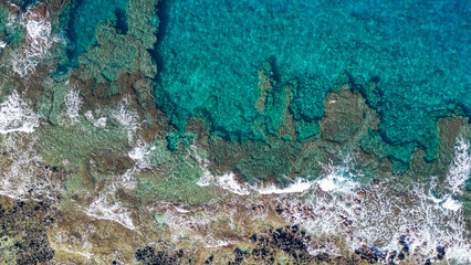 A top down aerial photo of the blue waters of Hawaii and coral reefs off of the Big Island. With beautiful blue colors and texture of land