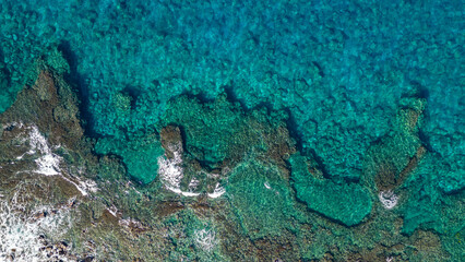 A top down aerial photo of the blue waters of Hawaii and coral reefs off of the Big Island. With beautiful blue colors and texture of land