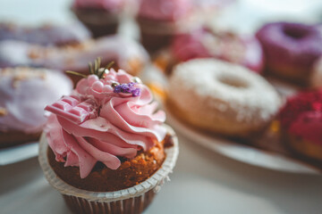 Vanilla cupcakes with cream cheese frosting and pink sprinkles on pink background. Saint Valentine's day or birthday dessert