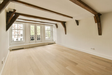 an empty room with wood flooring and exposed wooden beams on the ceiling, looking towards the entrance to the living room