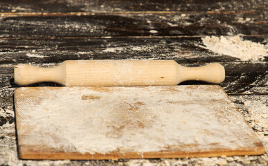 wooden board and rolling pin with flour for making dough.