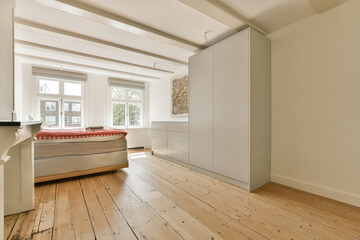Fototapeta premium a bedroom with white walls and wood flooring in the middle of the room, there is a bed on the other side