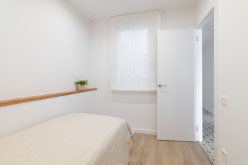 Fototapeta na wymiar Bed with blanket and narrow shelf on wall in white bedroom