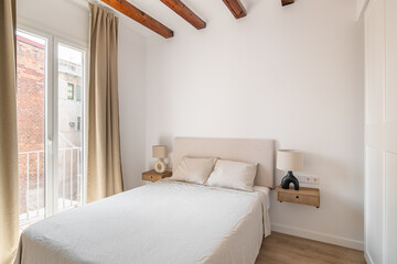 Comfortable bed with pillows in white minimalist bedroom