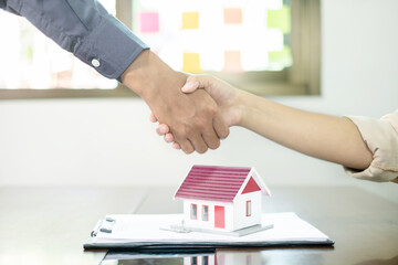 Businessmen and brokers real estate agents shake hand after completing negotiations to buy houses insurance and sign contracts. Home insurance concept