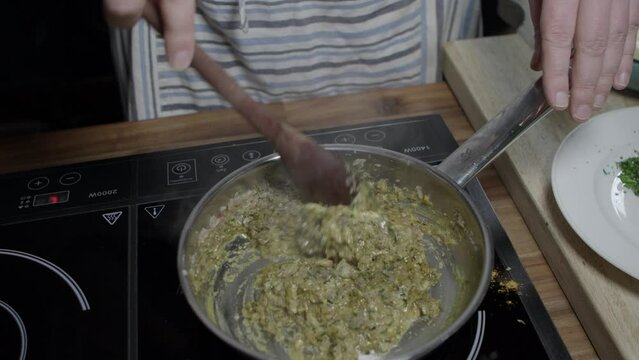 A chef mixing ingredients in a metal pan. Preparing delicious caf&eacute; de paris sauce for steaks. No face.