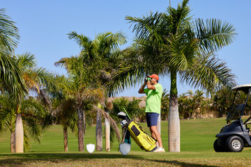The golfer accurately measures the distance to the flag in a golf course with the laser rangefinder.