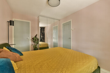 a bedroom with pink walls and yellow bedspremed comforter in the middle of the room is a mirror on...