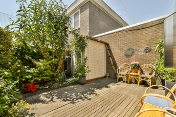 a backyard area with chairs and plants on the side of the house that is being used as an outdoor...
