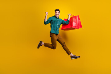 Fototapeta na wymiar Photo of cheerful crazy man wear trendy clothes running empty space showing fist hand isolated on yellow color background