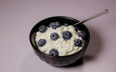 Close up of cottage cheese with fresh blueberries in black bowl, hight protein dessert