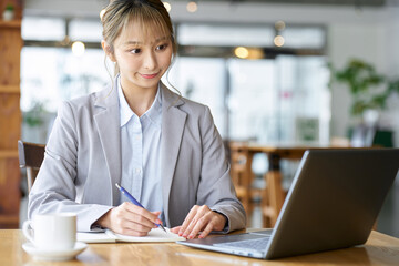 カフェでパソコンを使い勉強をするアジア人女性