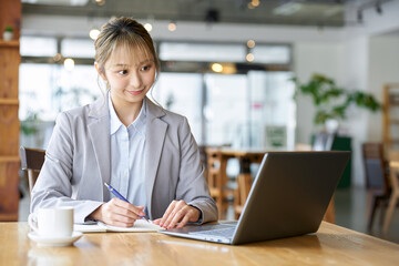 カフェでパソコンを使い勉強をするアジア人女性