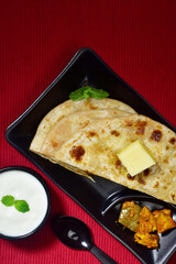 Top view of butter paratha with curd and aachar