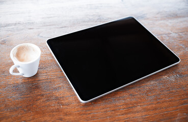 Tablet computer and cup of coffee on old wooden desk