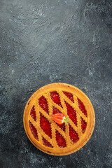 Homemade whole strawberry jam tart with jam on a wooden board, vertical image. top view. place for text