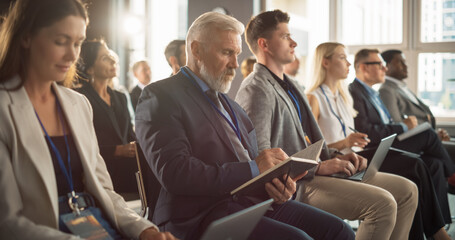 Senior Caucasian Man Sitting in a Crowded Audience at a Business Forum. Corporate Delegate Taking...