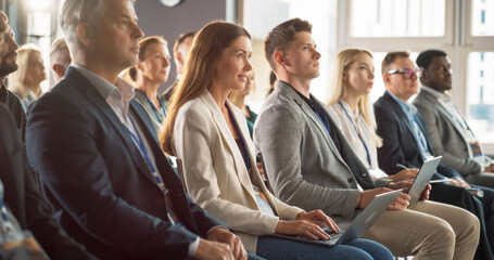 Young Woman Sitting in a Crowded Audience at a Business Conference. Female Attendee Writing...