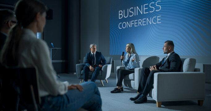 International Business Conference: Caucasian Female Tech CEO Talking With Male Host In Front Of Audience Of Diverse Attendees. Successful Woman Delivering Inspirational Speech For Women In Leadership.