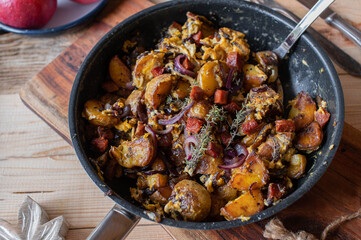 Fried potatoes with chorizo, scrambled eggs and red onions in a frying pan