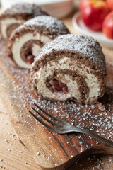 Fototapeta na wymiar Swiss roll with butter cream and cherries on wooden table