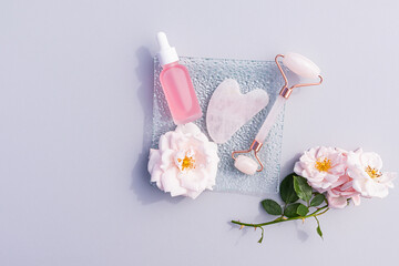 Quartz massager and home massage scraper with cosmetic oil in bottle with dropper on grey background. Top view. Flat layout. A copy space.