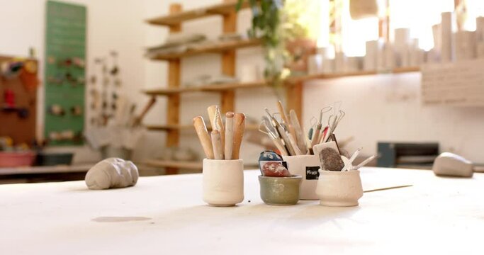 Brushes, pottery tools and clay on desk in pottery studio