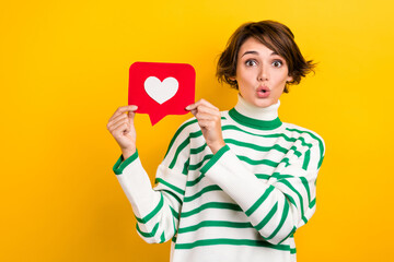 Photo of cute impressed girl dressed striped sweater big eye showing positive feedback card isolated yellow color background