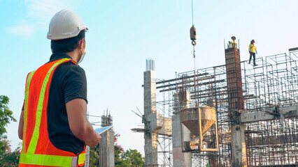 Asian engineer is delivering concrete pouring work at a construction site.