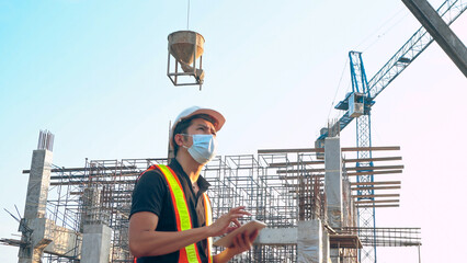 Asian engineer using tablet is delivering concrete pouring work at a construction site.