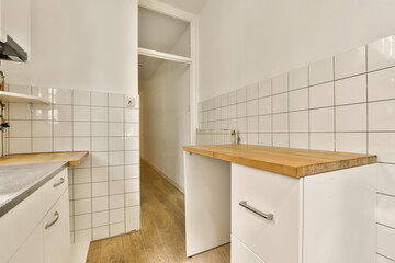 a kitchen with white tiles and wood counter tops on the island in front of the sink is wooden flooring