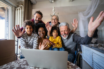 Happy multi-generation diverse family gathering around notebook and having fun during a video call - obrazy, fototapety, plakaty