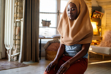 Young muslim black woman praying at home