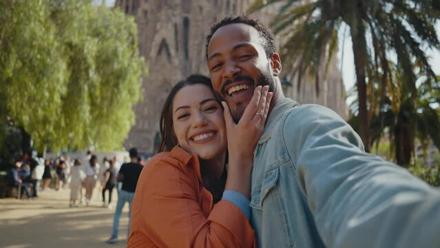 Young multiethnic couple visiting and dating in the center of Barcelona. Travelers on vacation exploring the city and the main landmarks and famous places