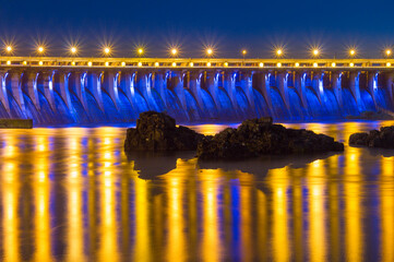 Evening view of Dneproges hydroelectric dam illuminated in blue and yellow colors, Dnieper river, Zaporizhzhia, Ukraine